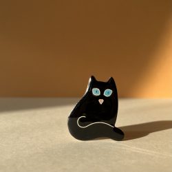 Broche en forme de chat assis, au pelage noir et aux yeux bleus, en émaux sur cuivre cloisonnés.