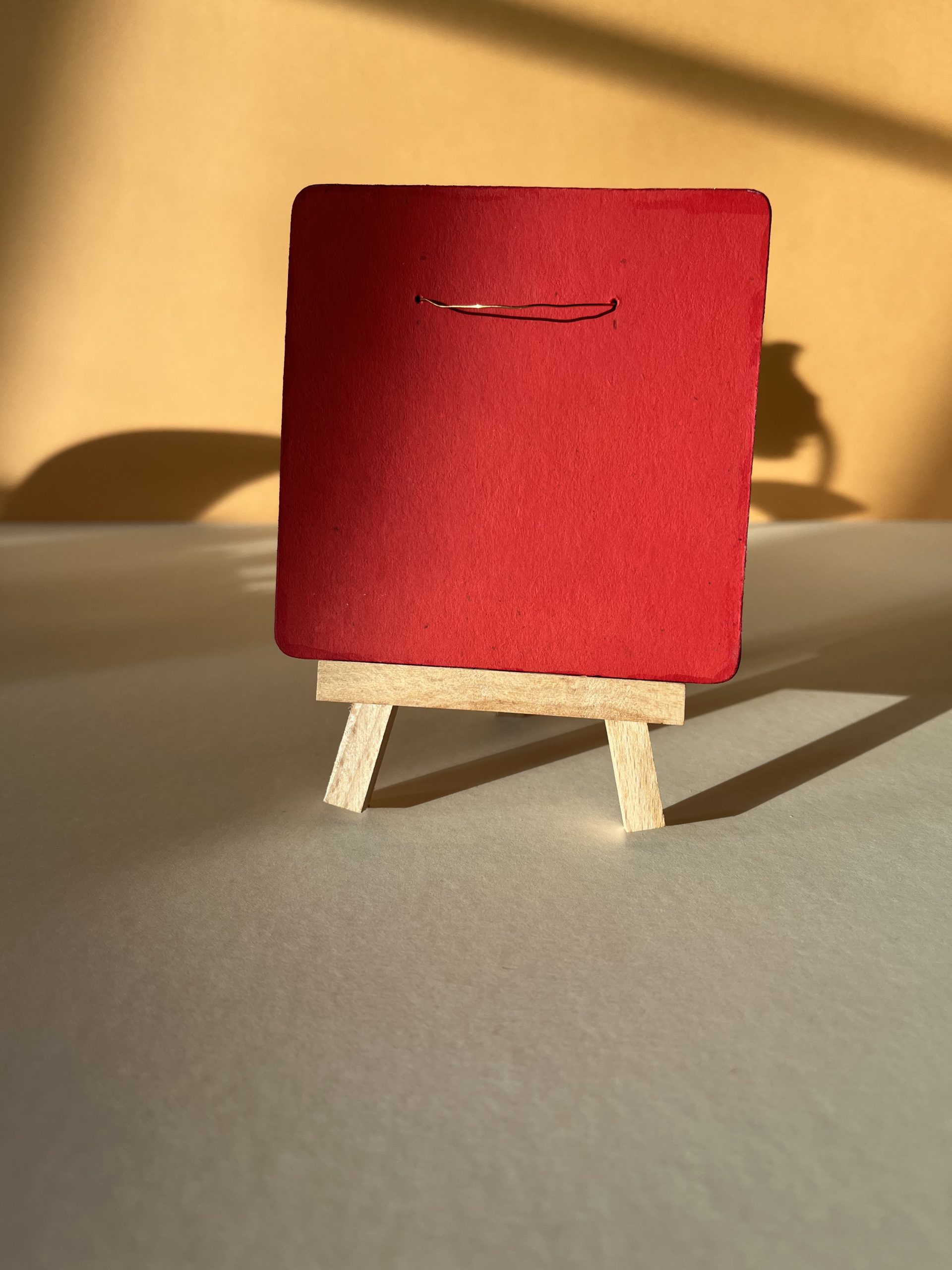 Verso tableau Fleurs Sauvages. Il est peint en rouge et possède un fil de cuivre qui permet d'accrocher l'oeuvre au tableau